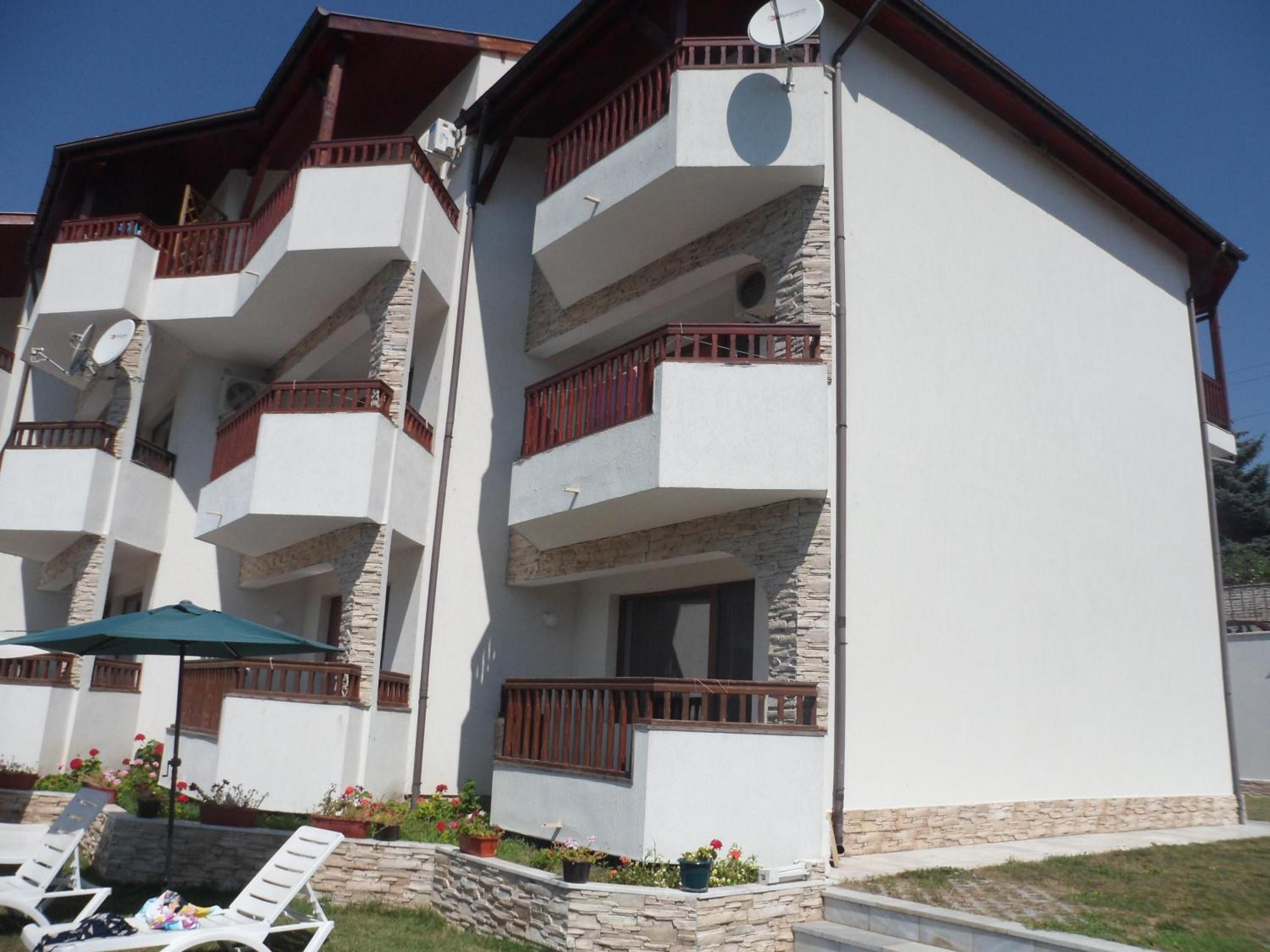 A multi-story building with balconies, a satellite dish, and outdoor seating.
