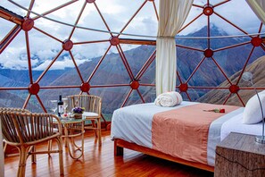 Una habitación con una cama, una silla, una mesa y vistas a las montañas.