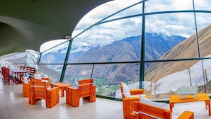 A restaurant with a view of mountains through large windows. - Vertical Sky Luxury Suites (Ollantaytambo)