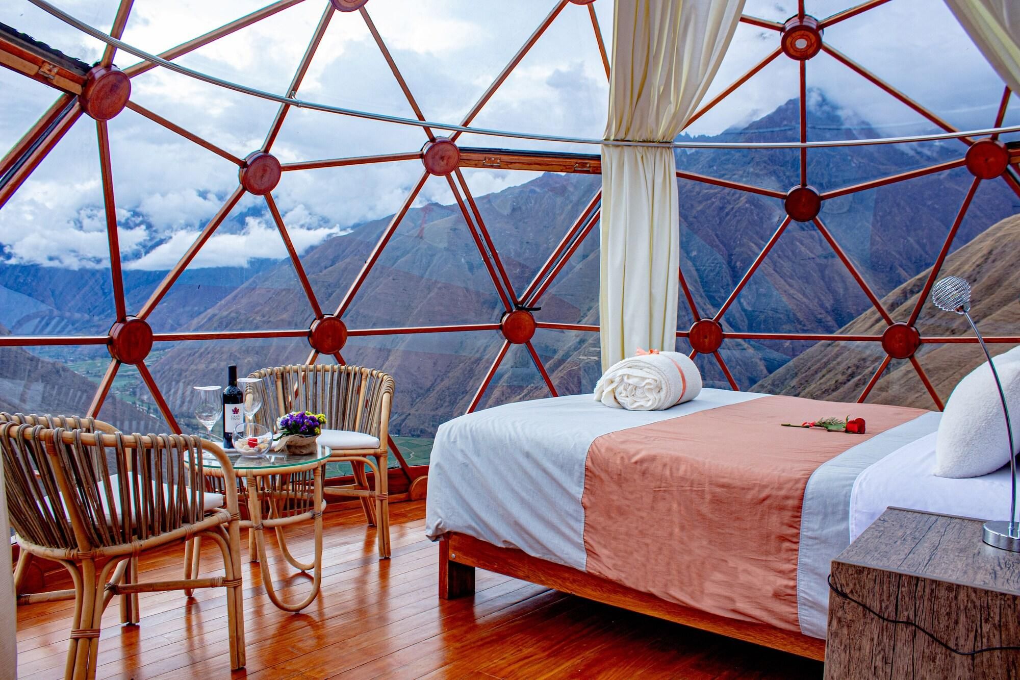 Ein Zimmer mit einem Bett, einem Sessel, einem Tisch und Bergblick.