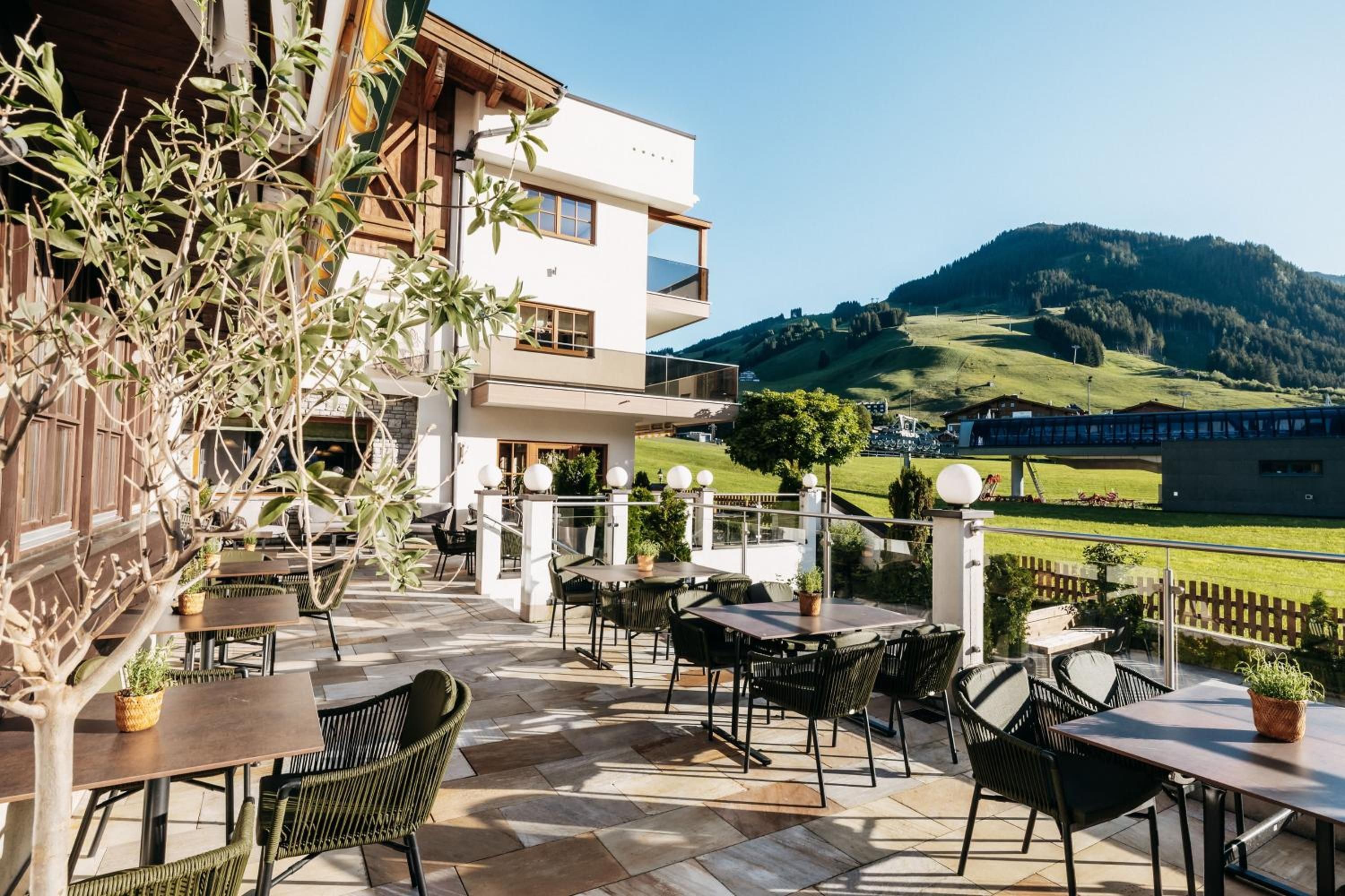 Une terrasse extérieure, dotée de tables et de chaises, qui offre une vue sur un paysage montagneux.