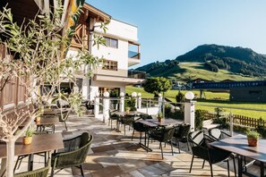 Una terraza al aire libre con mesas y sillas, con vistas a un paisaje montañoso.