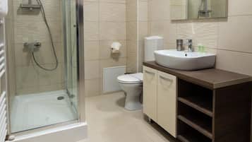 Ein modernes Badezimmer mit einer Duschkabine, einer Toilette und einem Waschtisch inklusive Spüle und Spiegel.