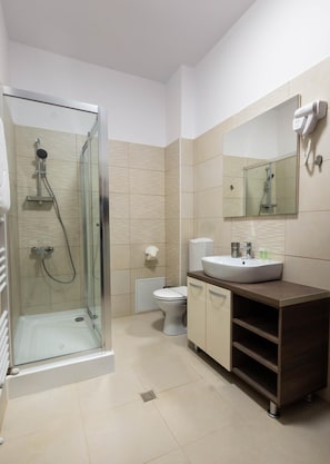 A modern bathroom with a glass-enclosed shower, a toilet, and a vanity with a sink and mirror.