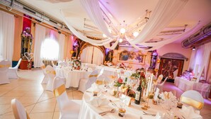 A banquet hall with round tables, white tablecloths, and gold sashes on chairs. - Burg Rooms 24h Self Check In (Spielberg)