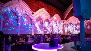 A bar area with ornate columns, a round table, and a brick wall in the background. - Burg Rooms 24h Self Check In (Spielberg)