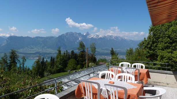 Una terraza con mesas y sillas con vistas a un paisaje montañoso y un lago.