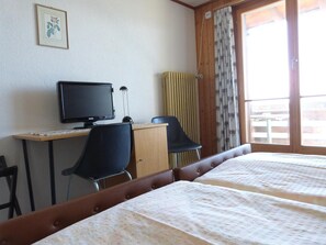 A room with two beds, a desk with a computer, a chair, and a window with curtains. - Hotel Bellevue (Heiligenschwendi)