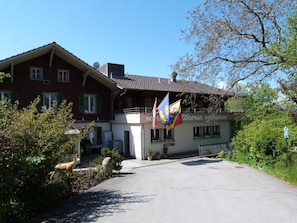 A hotel with a red facade, multiple windows, and flags. - Hotel Bellevue (Heiligenschwendi)