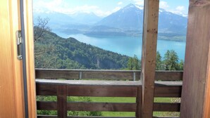 Un balcón de madera con vistas a un lago y montañas.