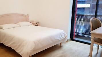A bedroom with a bed, bedside tables, a chair, and a window with a view.