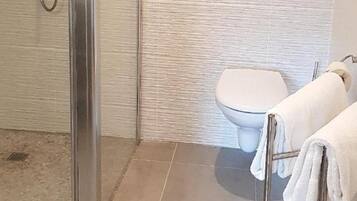 A bathroom with a shower, toilet, and a towel rack.