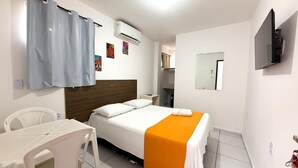 A hotel room with a bed, a desk, a chair, an air conditioning unit, a television, and a mirror. - Pousada Granville (Campina Grande)