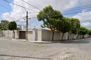 Una calle residencial con pavimento, aceras y una fila de árboles. Se observan postes de electricidad con cables aéreos.