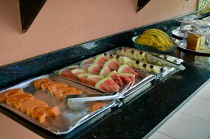 Un bufé con diversas frutas y un pastel sobre una encimera negra.