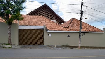 Um edifício residencial com telhado de telhas, portão fechado e um poste de eletricidade com fios.