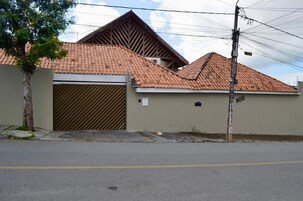 Un edificio residencial con techo de tejas, entrada protegida por una reja y un poste de electricidad con cables.