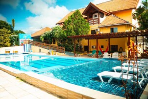Una piscina con sillas de descanso y un área techada con techo de madera.