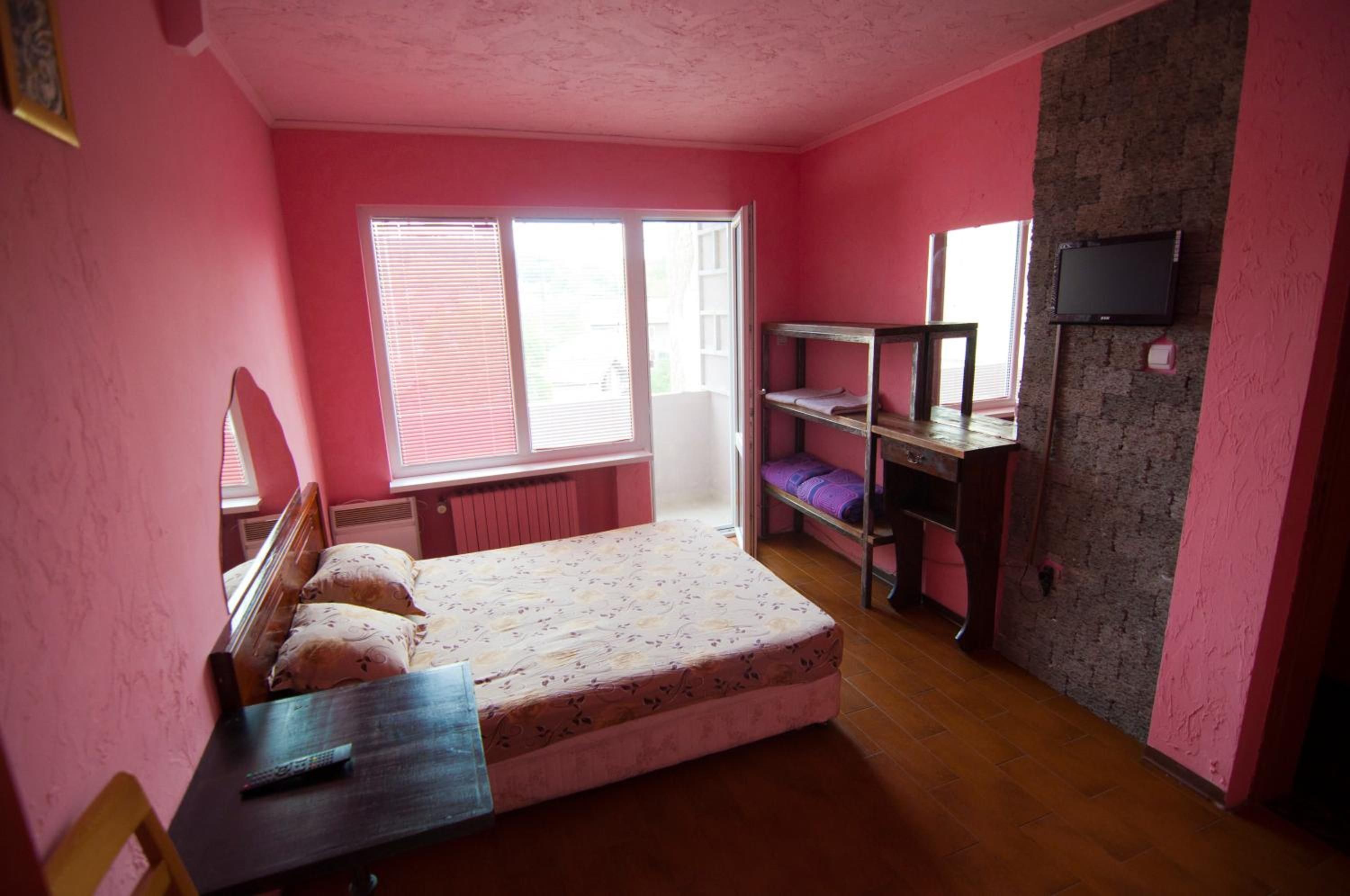 Une pièce comprenant un lit, un bureau, une chaise, un téléviseur et une fenêtre.