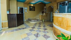 Un vestíbulo de hotel con un mostrador de recepción, una escalera y un escritorio.