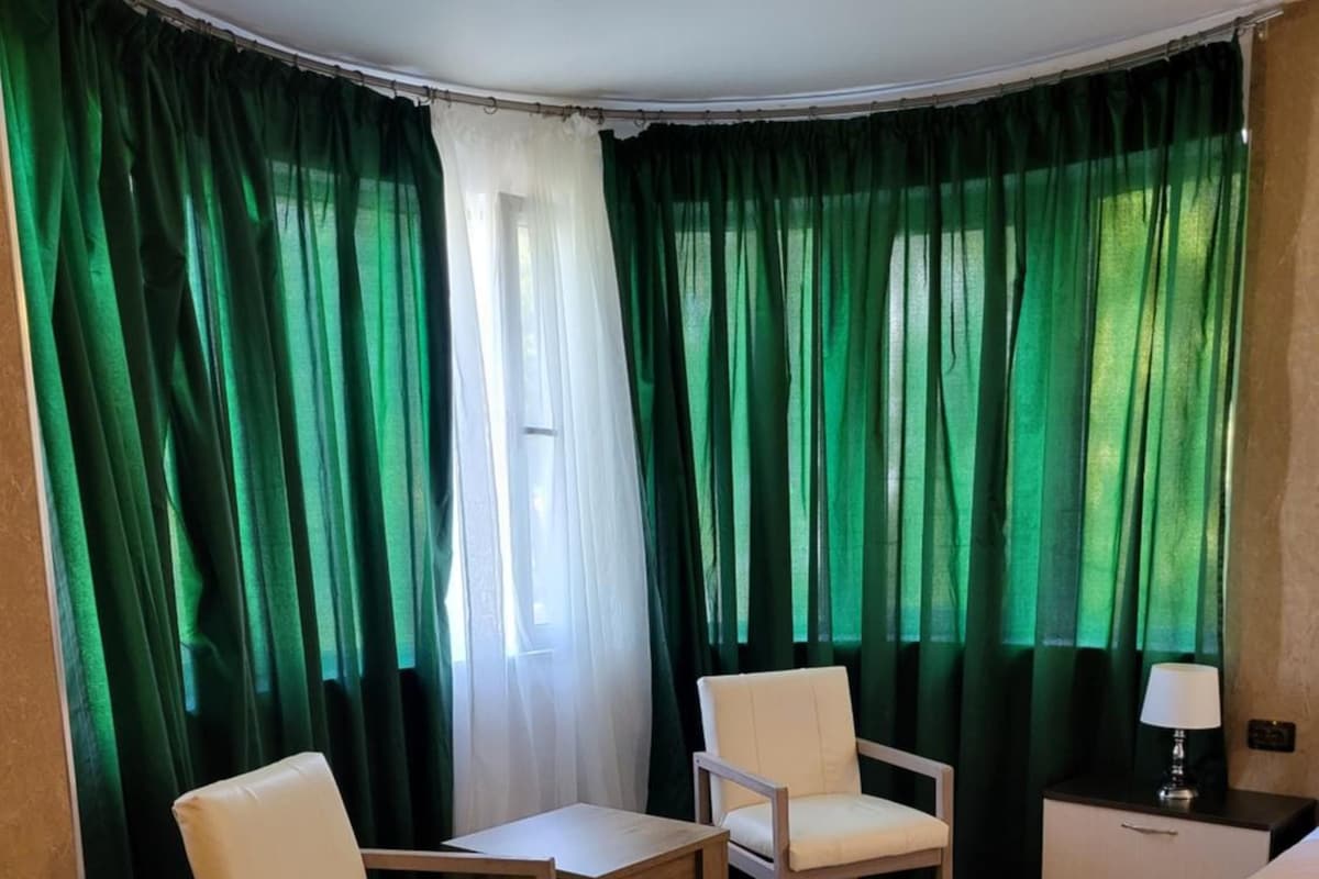 A hotel room with a bed, two chairs, a small table, and a nightstand.