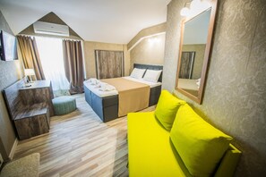 A hotel room with a bed, a desk, a chair, a sofa, and a mirror.
