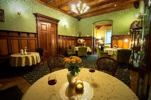 Un comedor con una mesa redonda, sillas, un jarrón con flores y una vela encendida.