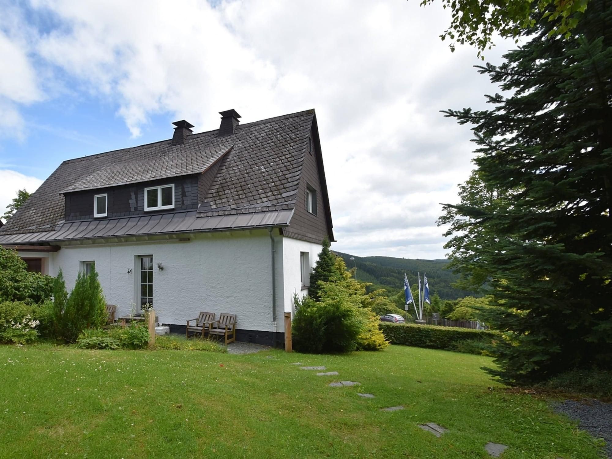 A two-story house with a sloped roof, a front porch, and a well-maintained lawn.