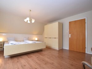 Un dormitorio con cama, mesitas de noche, un armario y una puerta.