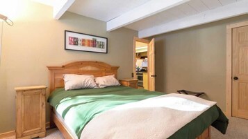 Un dormitorio con cama, mesita de noche, armario de madera y un cuadro enmarcado en la pared.