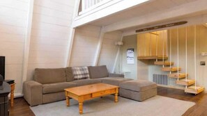 A modern living room with a sectional sofa, a wooden coffee table, and a staircase with wooden steps. - Zephyr By Avantstay Stylish Modified A Frame W/ (Truckee)