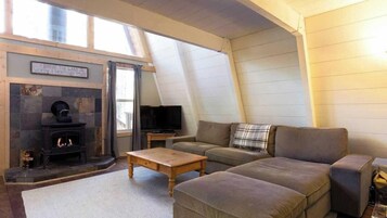 Una sala de estar acogedora con chimenea, un sofá, un televisor y una ventana con cortinas.