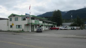 A motel with a green and white facade, a flag, and a pedestrian crossing sign.
