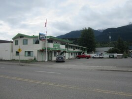 Um motel com fachada verde e branca, uma bandeira e uma placa de faixa de pedestres.