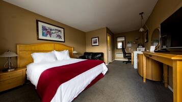 A hotel room with a bed, a desk, a chair, a television, and a framed picture on the wall.