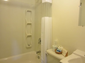 A bathroom with a bathtub, toilet, and shower curtain.