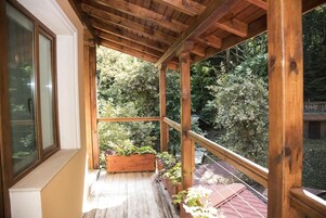 Una terraza cubierta de madera con una jardinera de madera y plantas en macetas.
