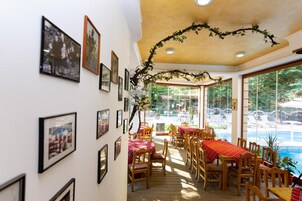 Un comedor con mesas y sillas, un techo decorado con una rama, y cuadros en las paredes.