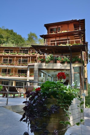 A multi-story building with balconies, large windows, and potted plants.