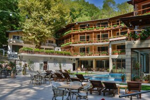 Un hotel con piscina, mobiliario exterior y balcones con plantas.