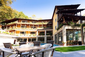 A multi-story building with a pool area, outdoor seating, and balconies with plants.