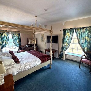 A four-poster bed with a red throw blanket, a television on the wall, and a window with curtains. - The Portaferry Hotel (Portaferry)