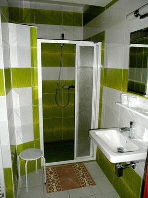 A bathroom with a shower, a sink, and a mirror.
