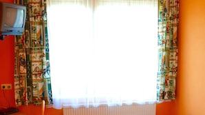 A room with a bed, a desk, a chair, a television, and a window with curtains. - Gasthof Redl (Oed-Öhling)
