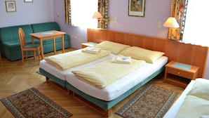 A hotel room with a double bed, a green sofa, a small table, two nightstands, and a patterned rug. - Gasthof Redl (Oed-Öhling)