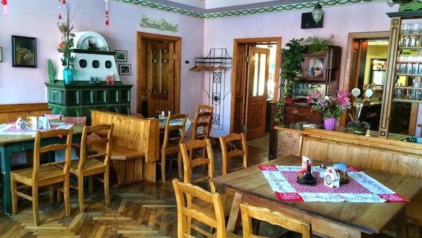 A dining area with wooden furniture, a herringbone floor, and a green cabinet. - Gasthof Redl (Oed-Öhling)