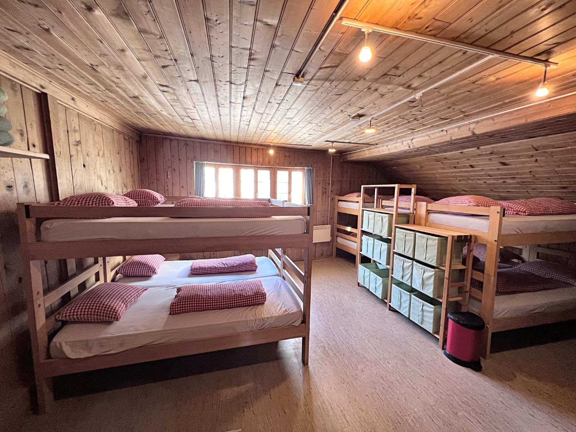 Ein Zimmer mit Etagenbetten, Holzwänden und einem Fenster mit Vorhängen.