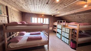 Ein Zimmer mit Etagenbetten, Holzwänden und einem Fenster mit Vorhängen.