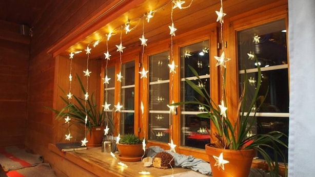 A wooden cabin with a porch decorated with string lights and potted plants. - Jugendherberge Hospental (Hospental)