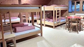 A room with bunk beds, a dining table, and chairs. - Jugendherberge Hospental (Hospental)